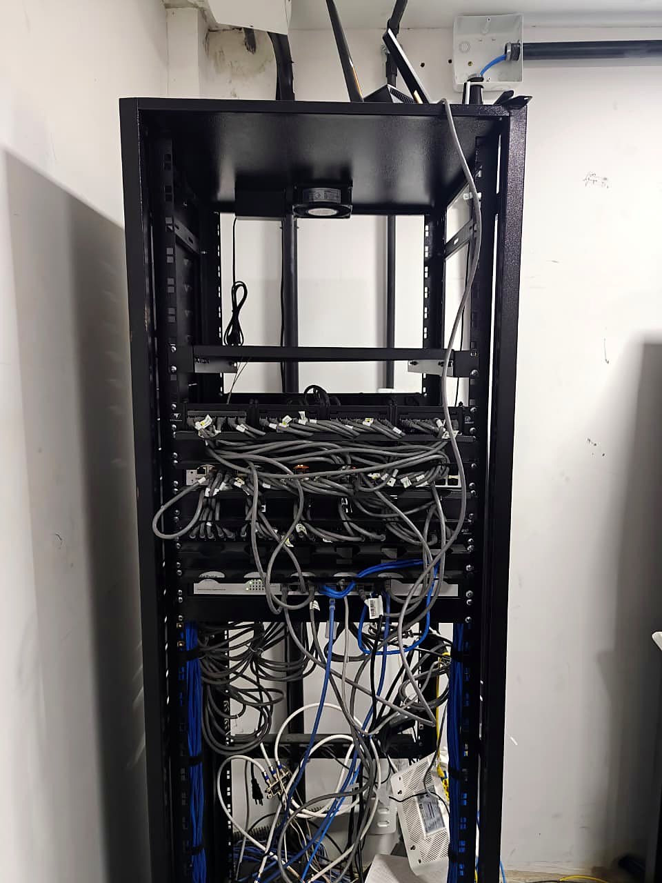 Rack antigo com cabeamento desorganizado antes da reestruturação na Contecom Distribuidora