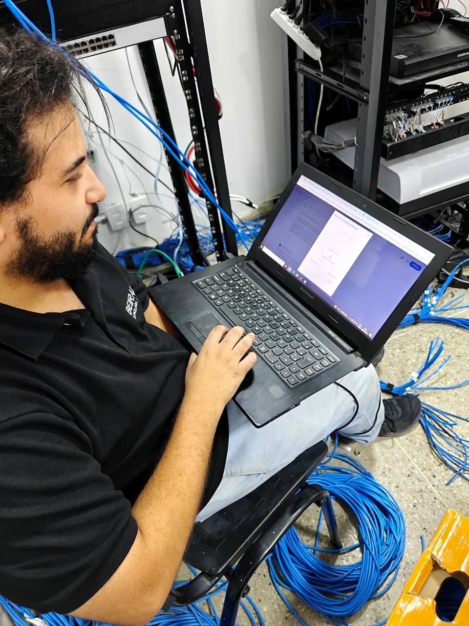 Técnico realizando a configuração dos equipamentos de rede pelo notebook