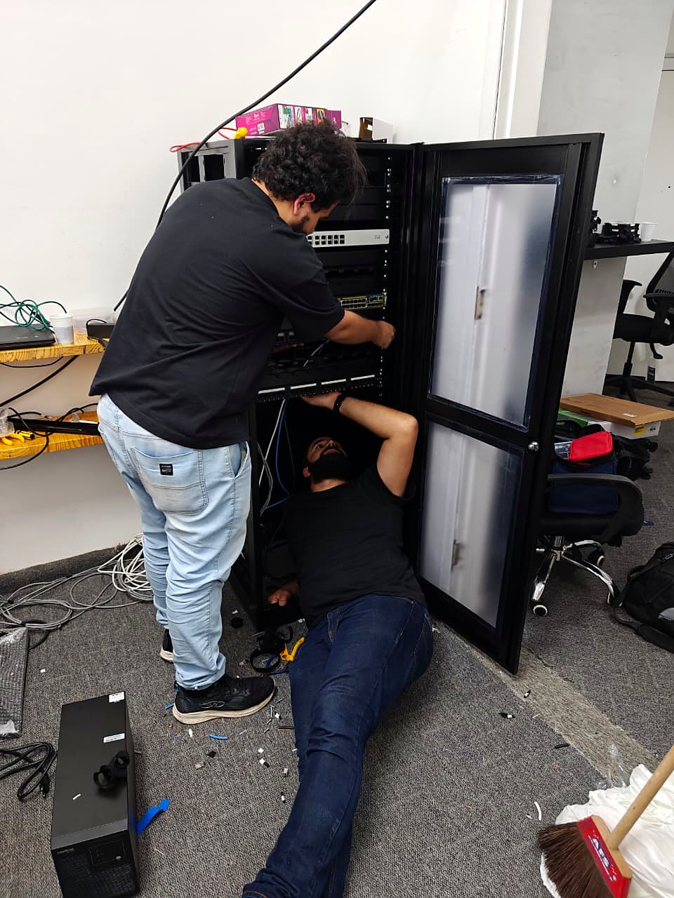 Equipe realizando a instalação dos equipamentos e do cabeamento no rack aberto