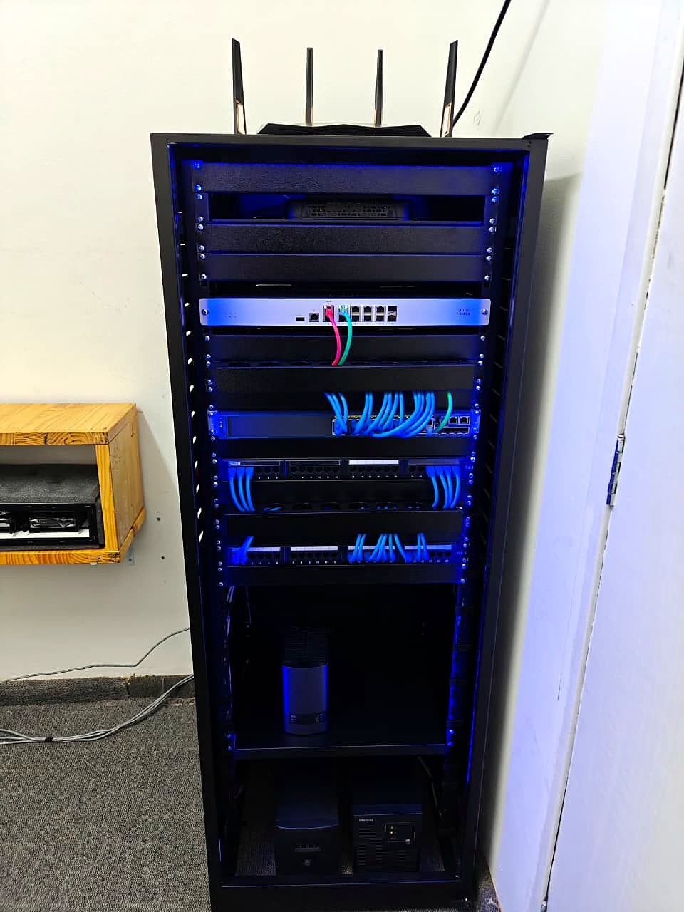 Vista completa do rack finalizado com equipamentos, nobreaks na base e iluminação LED azul nas laterais internas
