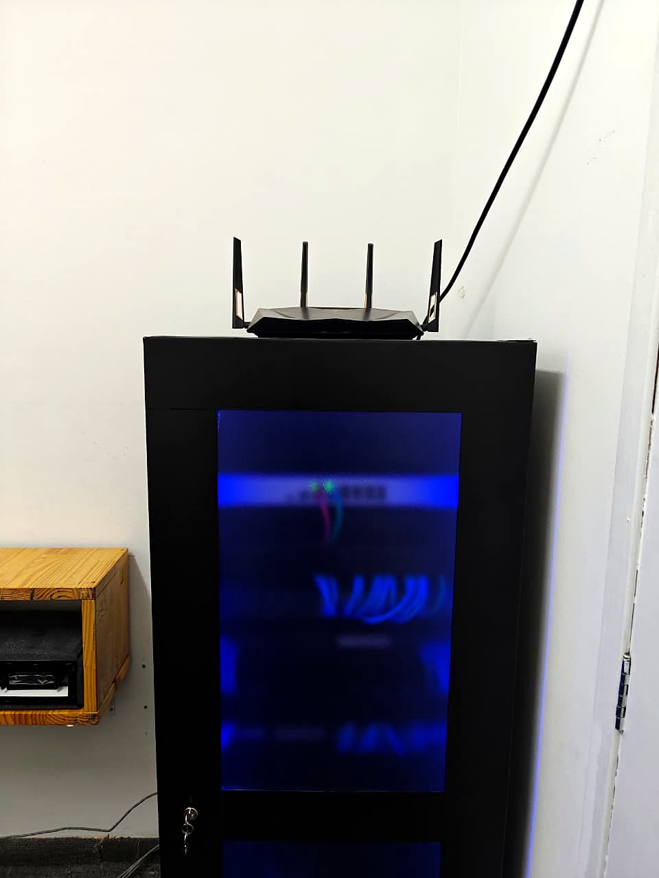 Rack fechado com porta de vidro e iluminação LED azul interna, com patch cords azuis organizados
